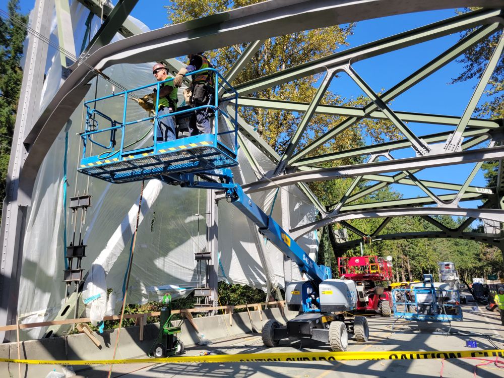 Construction workers on a lift repair a bent steel beam on the SR 410 White River Bridge.