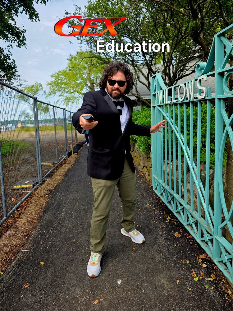 A man with a suit jacket, bow tie, and green pants on pointing a tv remote at the camera under the words Gex Education 
