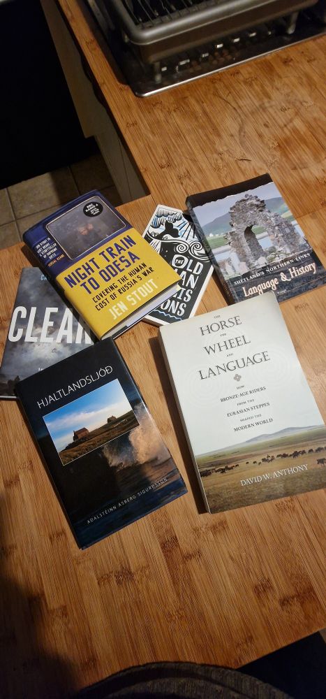 A selection of books on a bamboo worktop - 'Night Train to Odessa' by Jen Stout; 'The Horse, the Wheel and Language' by David W Anthony, 'Hjaltlandslod' by Aðalsteinn Sigurðsson, Shetland Language and History 