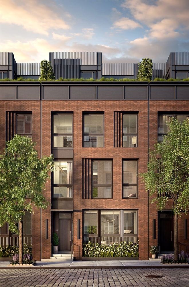 An image of a three-story townhouse on a modern paved street. The townhouse is made of bricks, and the road is paved with cobbles.