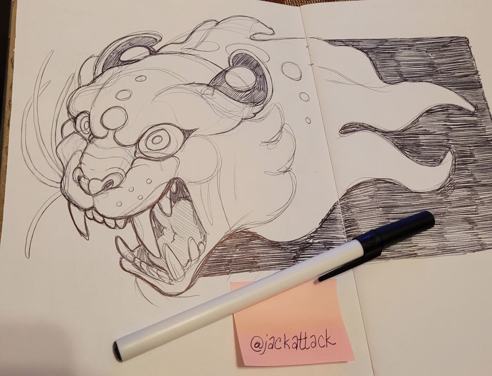 A sketch across two pages of a vaguely tiger-like monster cat head, mouth open. It's drawn in black ballpoint pen.