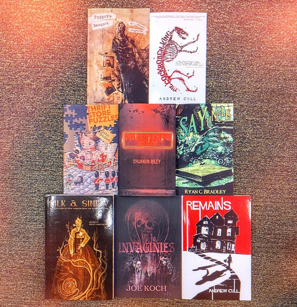 an assortment of horror books spread out on a floor 