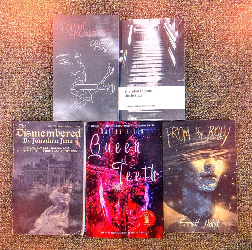 an array of horror books on a carpeted floor