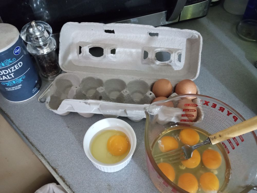 Twelve brown eggs on my kitchen counter, 8 broken into bowls. Salt and pepper just to their right.