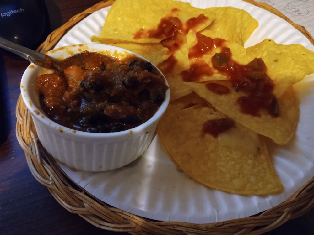 A plate of nachos with a side of Chilli Colorado+beans cooked separately.