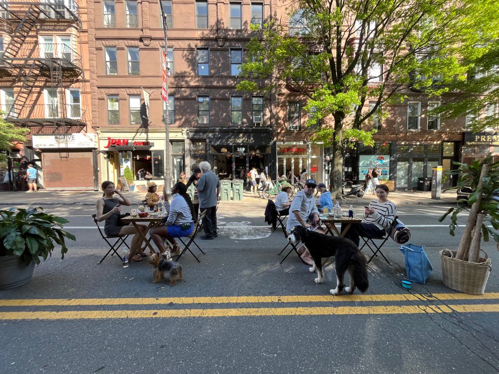 People sitting at outdoor tables on a city street. 
