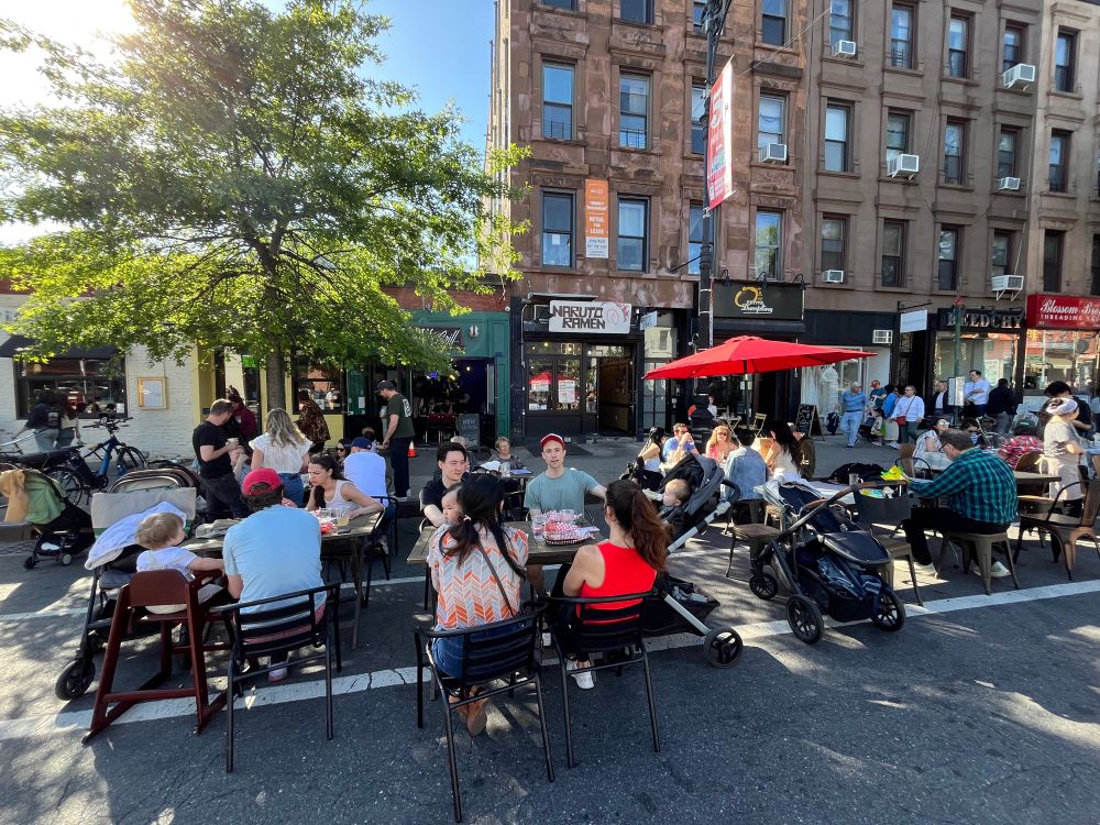 People sitting at outdoor tables on a city street. 