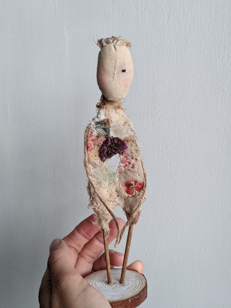 A habd holding a little doll with a hole in its middle. 