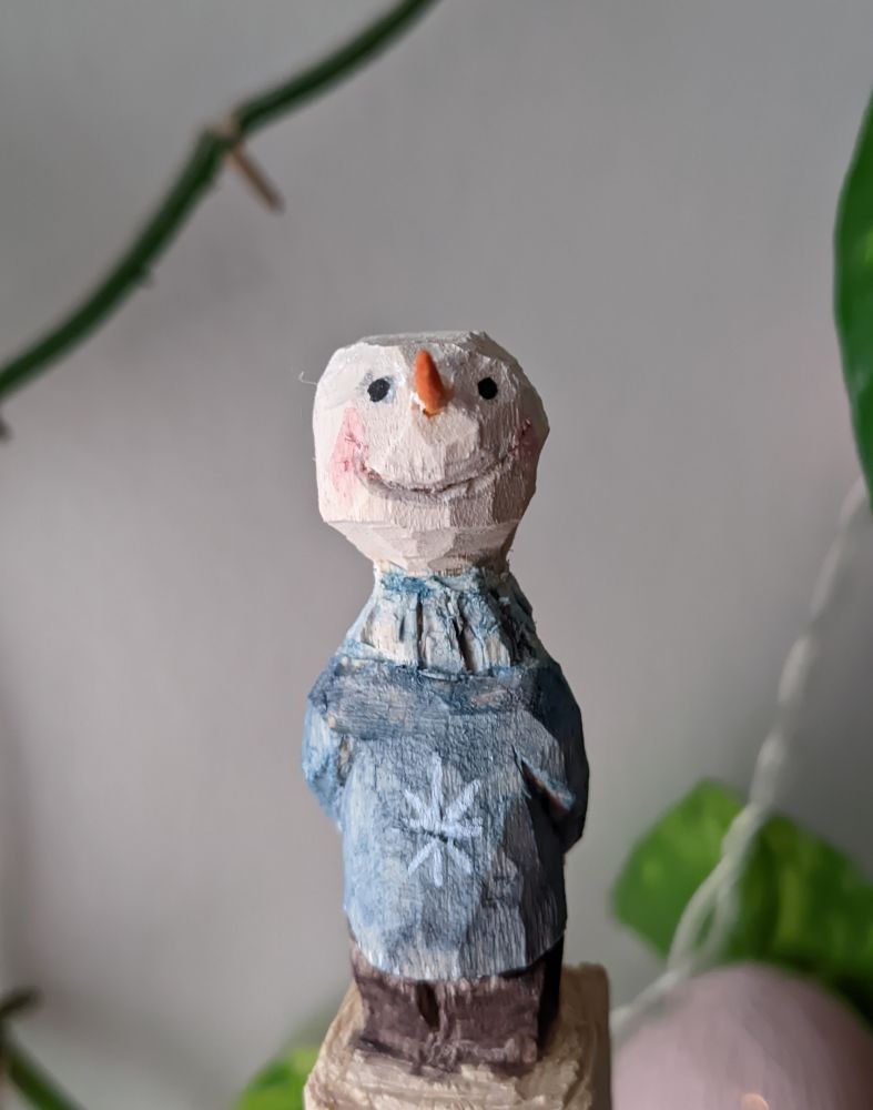 A little snowman carved in wood.
Big smile blue jumper.
It is a beginner work so it is full of mistakes but he still is a cute and happy little buddy. 