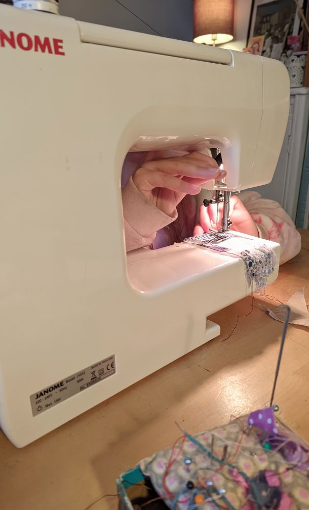 A little hand putting the pressing foot down on a sewing machine. 