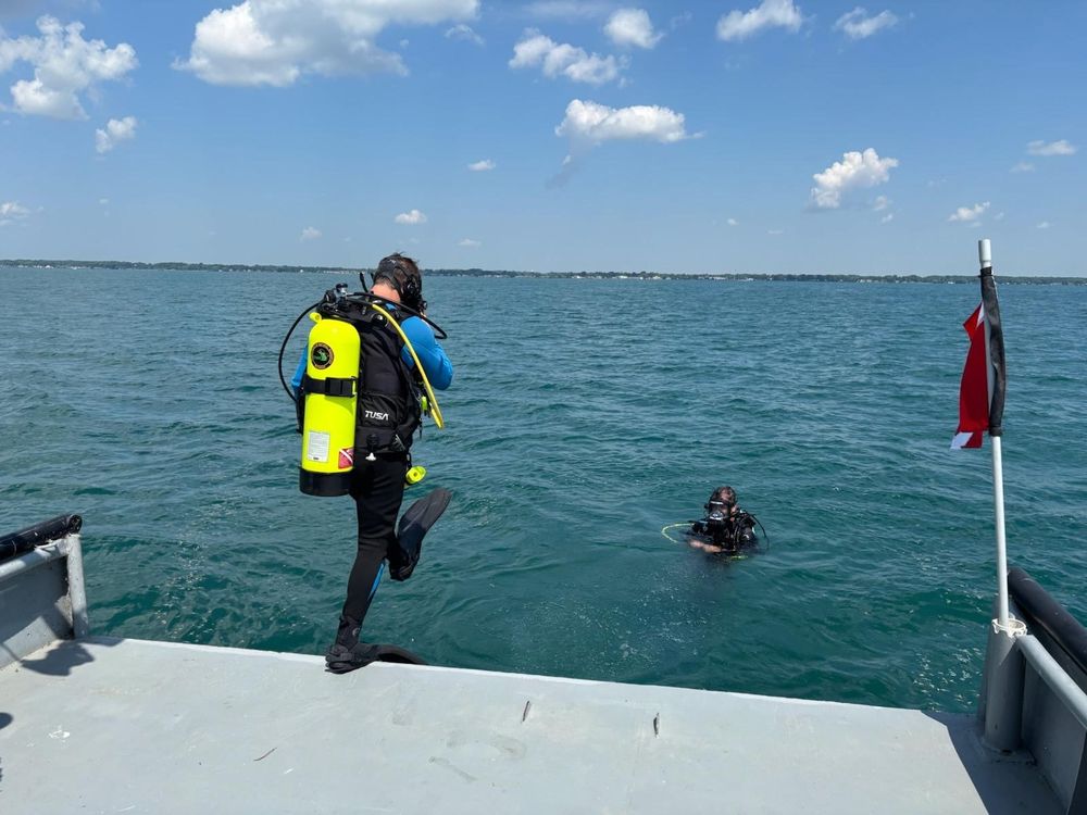 A scuba divers giant steps into the water