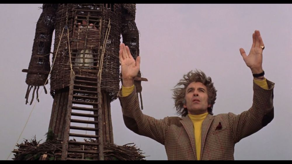 Image from the Wicked Man (set on Summersisle) - a wild haired man holds his hands apart in a 'it was that big' gesture