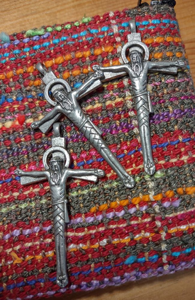 Unpolished pewter crucifixes on top of a Saori woven zipper pouch.