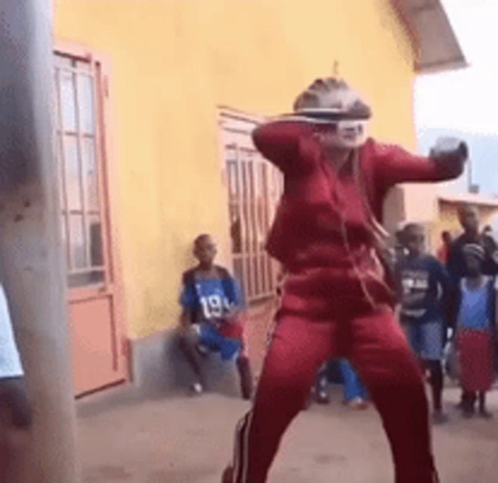 a man in a red suit is dancing in front of a group of people .