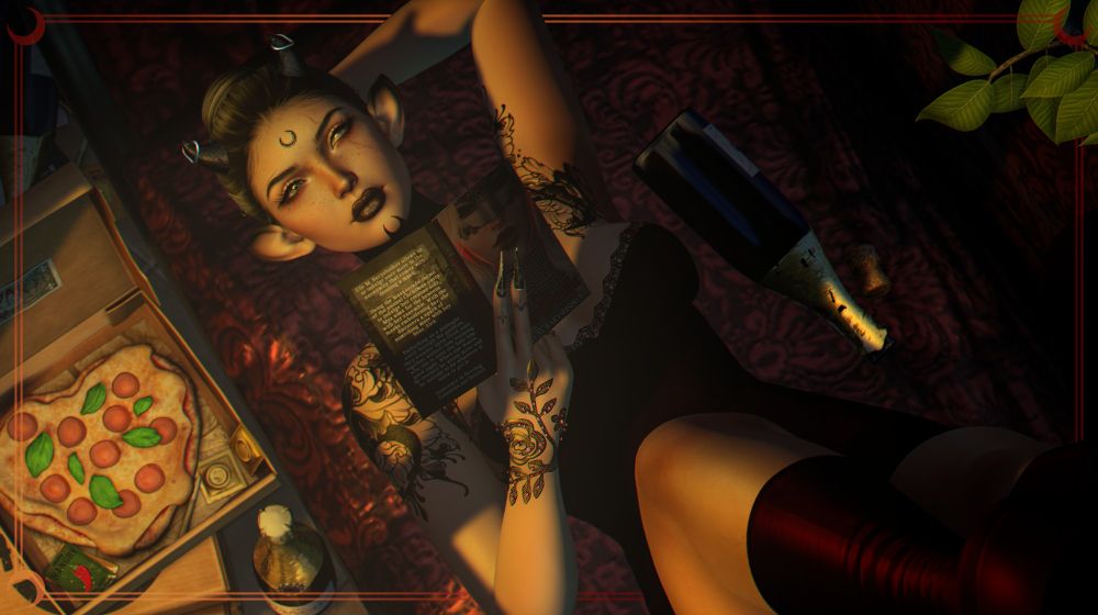 A horned and tattooed elven person with their hair tied back rests with an arm behind their head on a red cushioned lounge. Wearing a red camisole and red boots, they prop their feet up toward the edge of the image, looking up over a romance novel into the camera. Around them are green leaves, an open box with a heart shaped pizza, and opened and unopened bottles of wine.