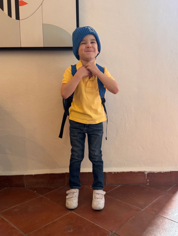 Picture of 4 year old boy in yellow polo shirt, blue jeans and white shoes with a blue sonic backpack and a blue sonic beanie. 