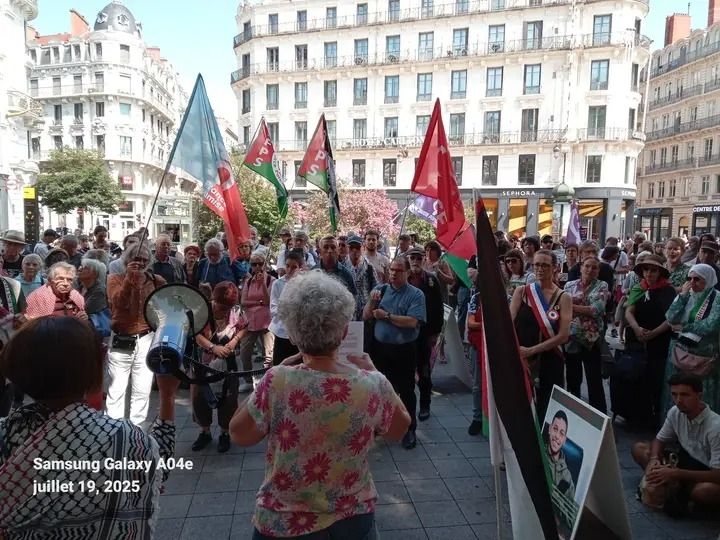 Intervention d'une militante de l'AFPS devant le rassemblement place de la République à Lyon avec des drapeaux palestiniens, PCF, Ensemble, LFI. 