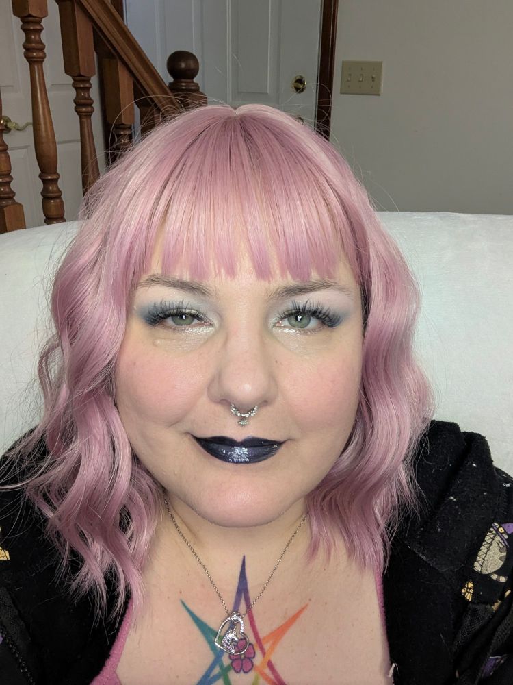 A person with pink hair and dark blue lips.