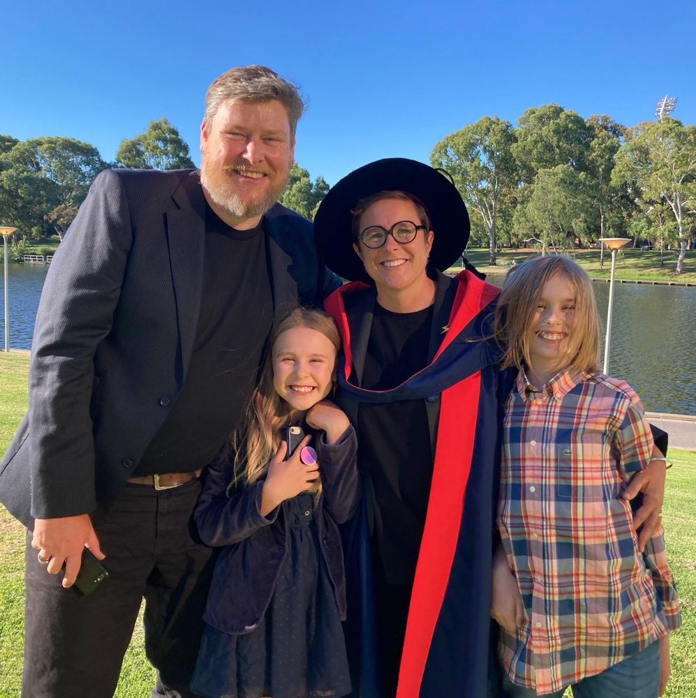 Lizzie in PhD graduation outfit with partner and our two kids. 