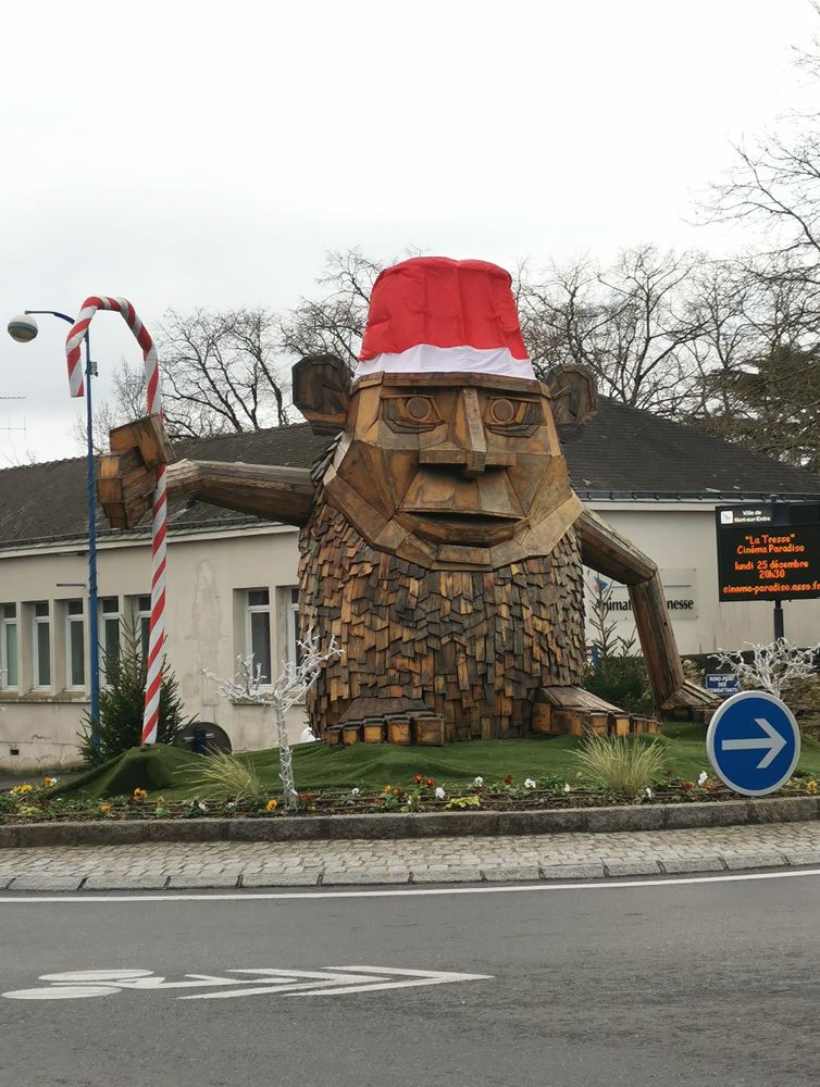 Photo d'un rond point sur lequel trône un grand singe en bois. Il porte un bonnet de père noël et tient dans sa main droite un sucre d'orge en guise de canne.