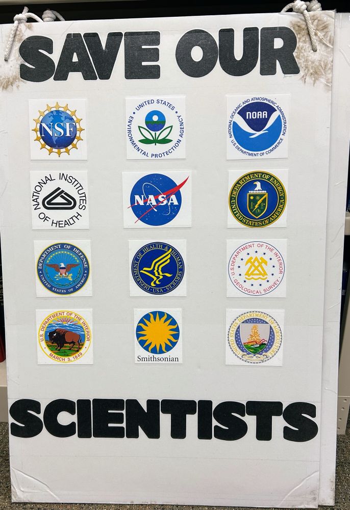 Poster board that says "Save our scientists" with symbols for 12 US federal agencies where scientists work