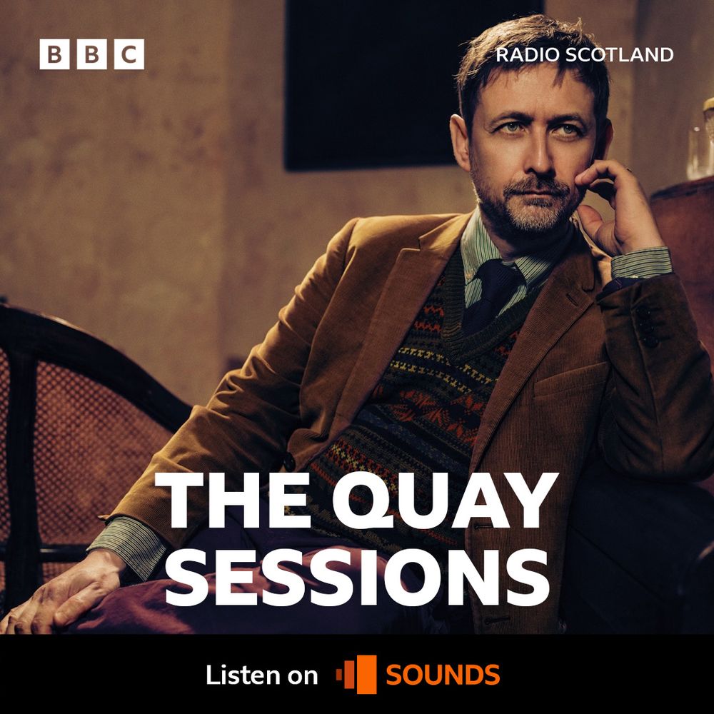 A photograph of Neil Hannon sat by a piano with his arm leaning on the lid. The text says The Quay Sessions. Roddy Hart will be playing our new single, Achilles, on BBC Radio Scotland. Tune in from 8pm on Wednesday 9th April.