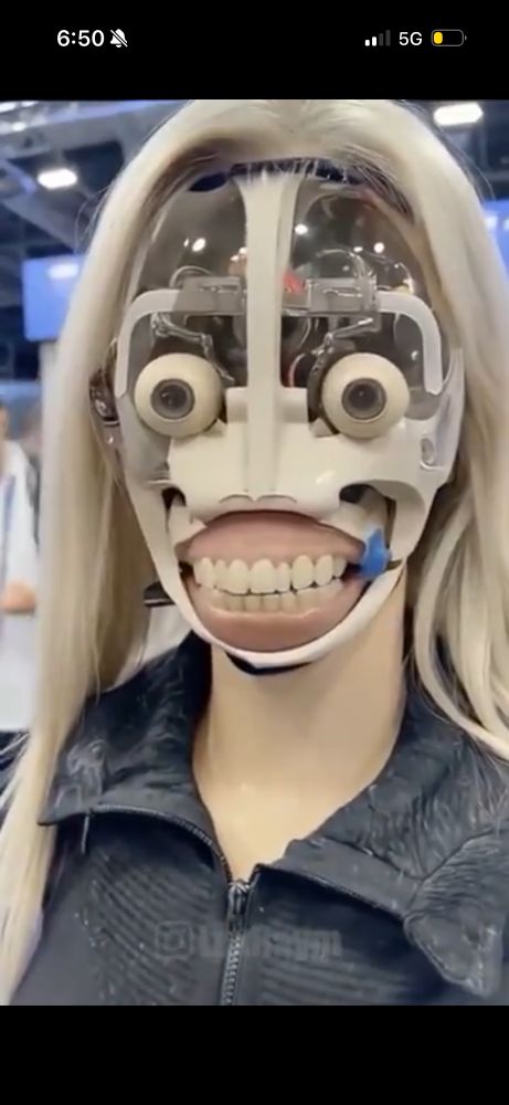 faceless bimbo robot with blonde wig staring directly into the camera, full range of teeth exposed