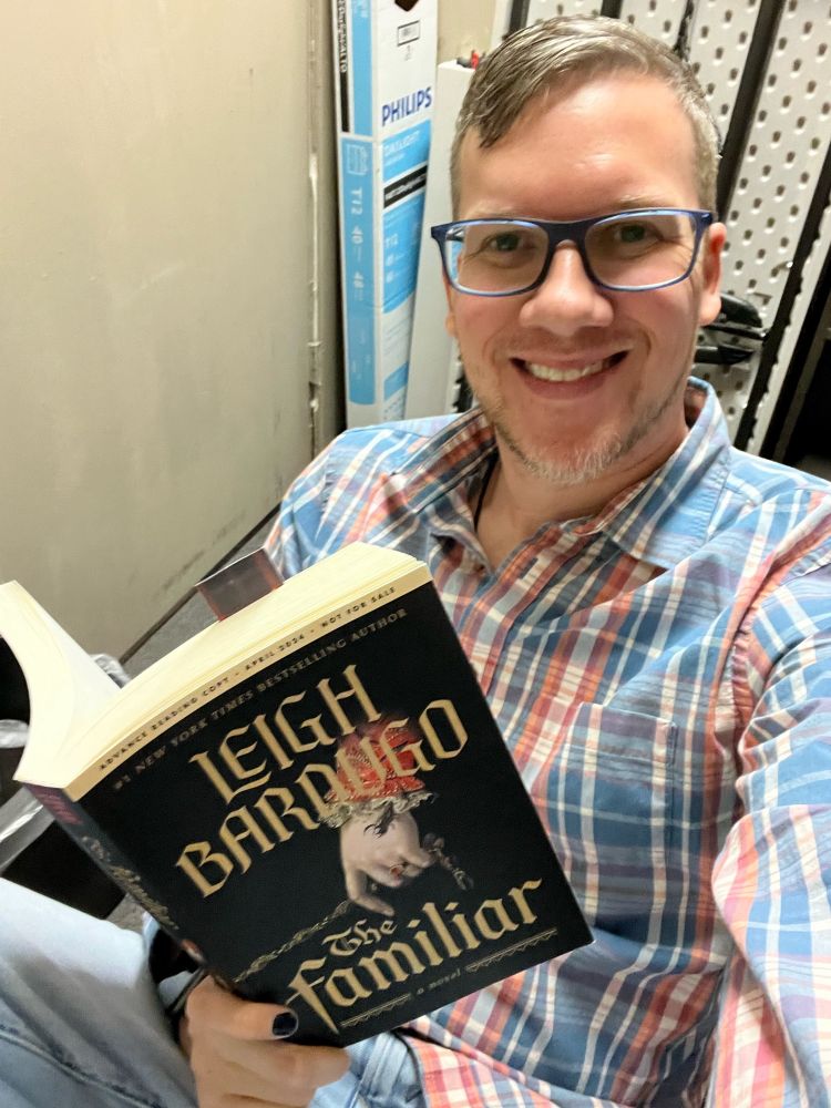 Lunch break selfie holding a copy of The Familiar by Leigh Bardugo