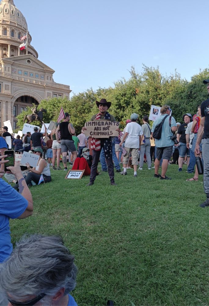 A man holding a sign that reads, "Immigrants are not criminals."