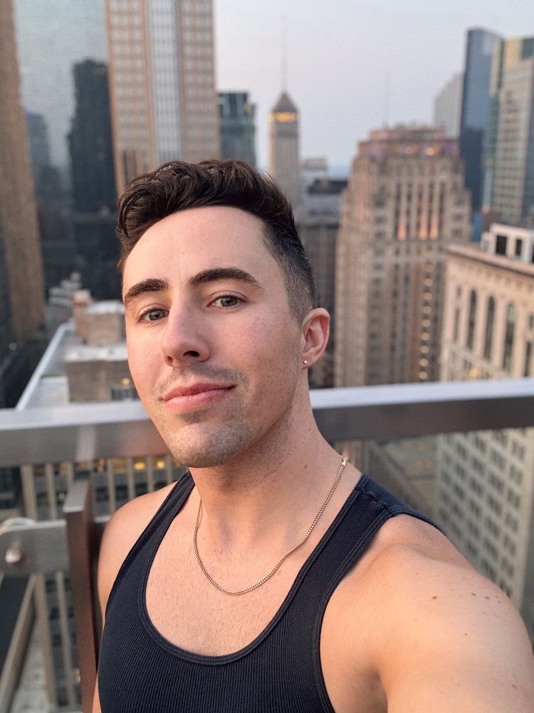 Selfie of a man (me) wearing a black tank top and a slutty little gold chain against background of downtown Minneapolis