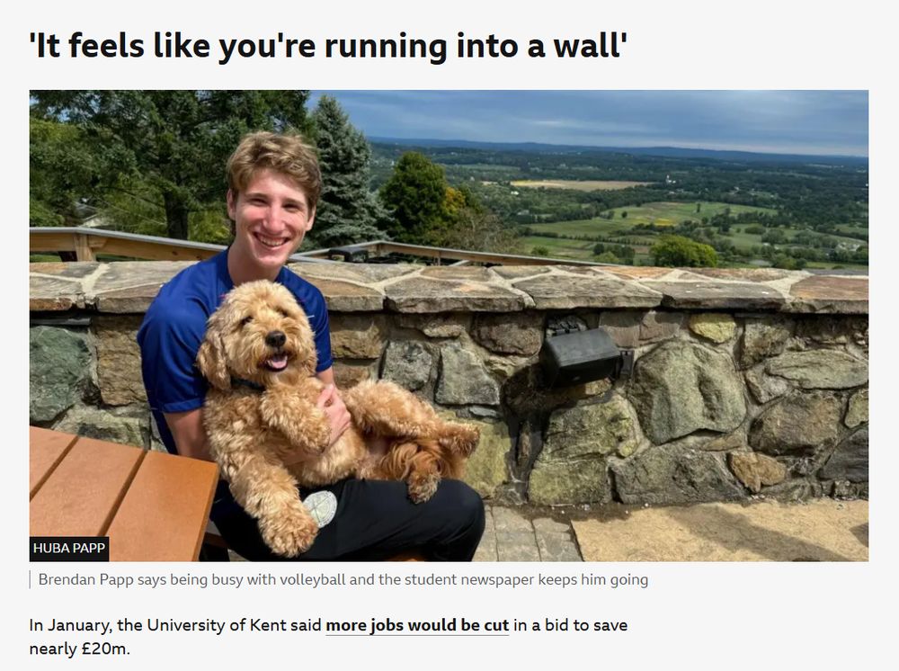 
A person sits on a stone bench holding a dog, with a scenic landscape in the background. There's a caption about being busy with volleyball and student newspaper keeping him going.