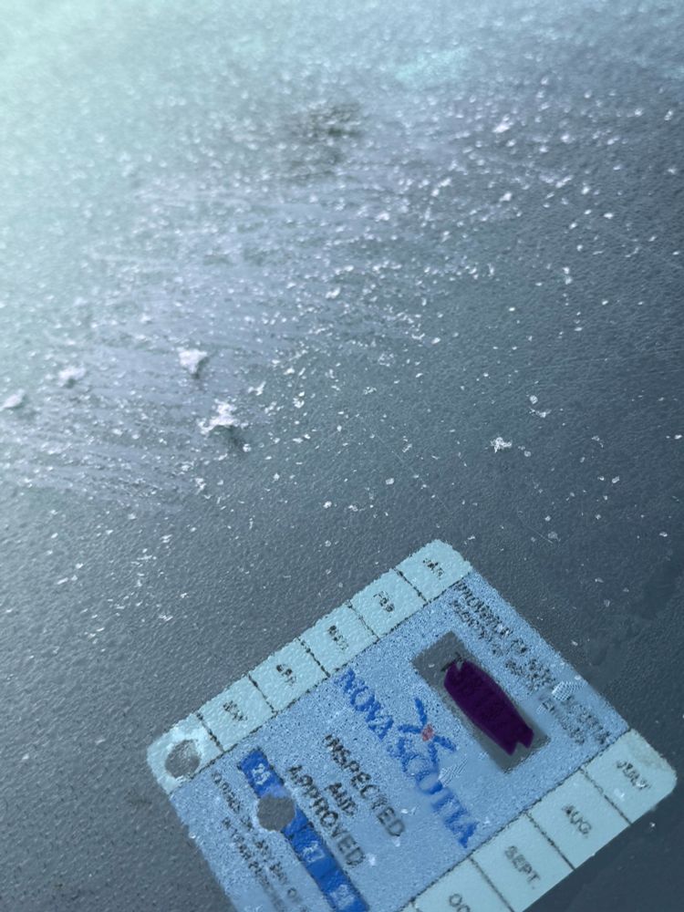 Close-up of the safety inspection sticker on my car windshield you can see where I’ve scraped the ice beside it