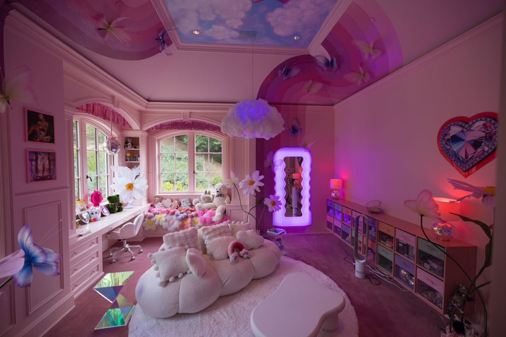 Whimsical room with plush seating, colorful cushions, and flower decor. Neon lights and vibrant murals create a dreamy, playful ambiance.
