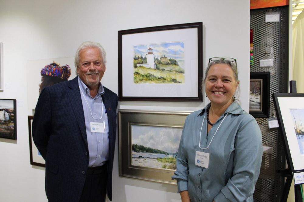 Shows two artists, Gary McFarland and Poppy Balser with their paintings hanging in the Open Water 2025 exhibition at Teichert Gallery in Halifax. 