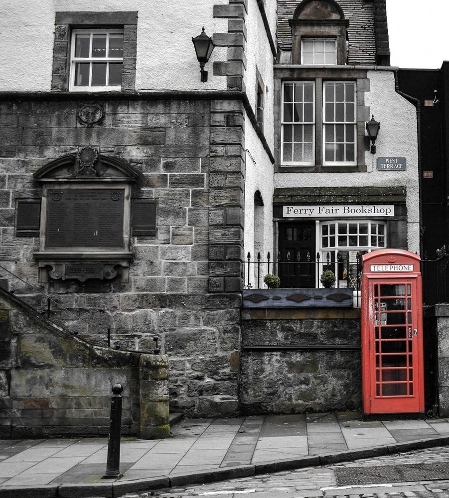 A cobbled street with beautiful traditional old buildings and a bright coloured old phone box, standing out against it's surroundings 