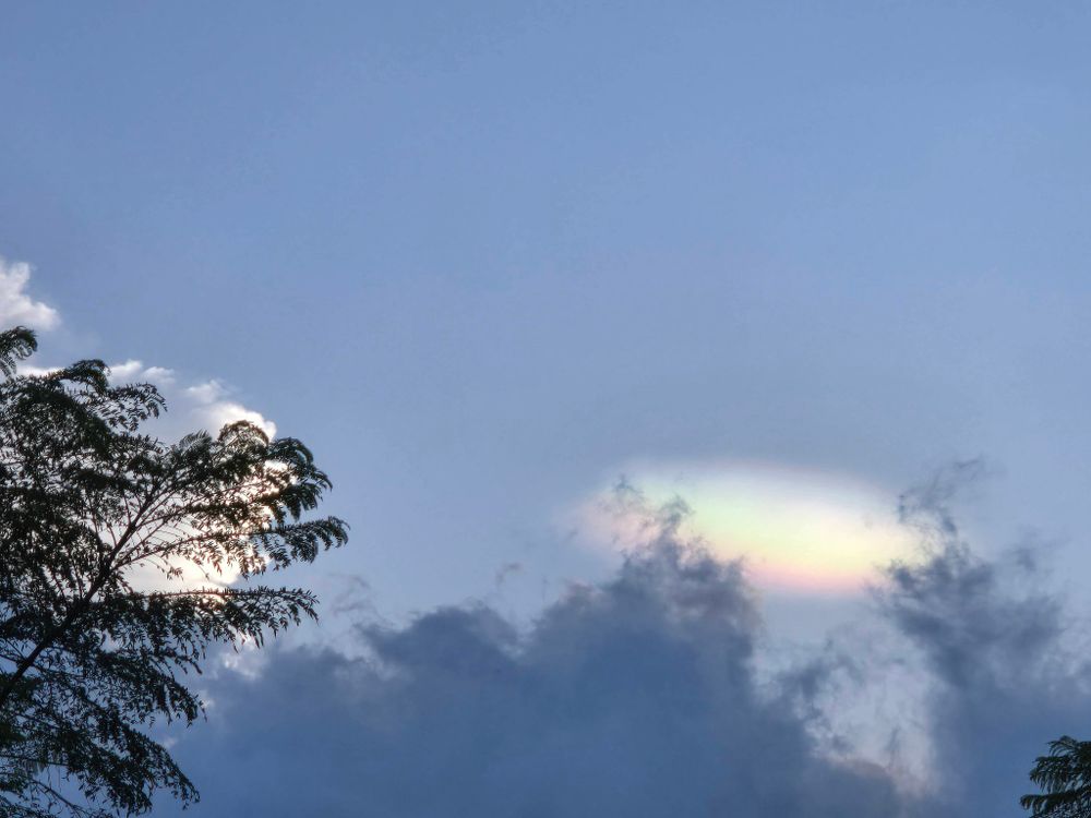 سماء زرقاء مع غيوم خفيفة بلون قوس قزح