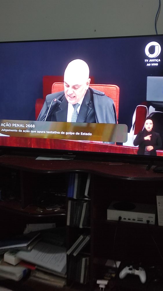Foto de uma televisão passando uma transmissão do canal de Youtube TV Justiça. Na tela aparece o ministro do STF Alexandre de Moraes.