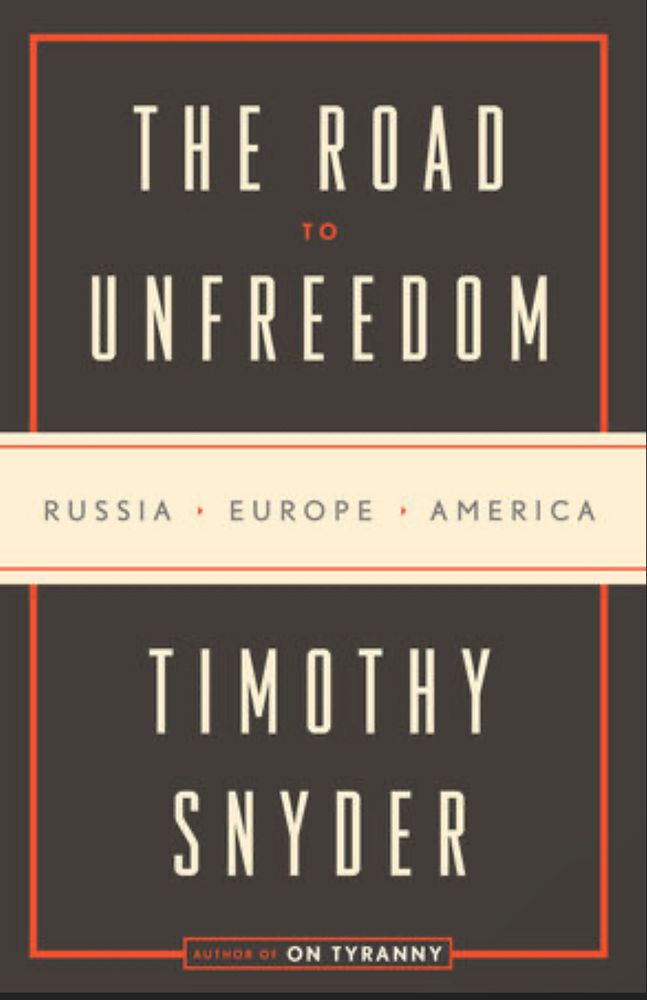 Image of book cover. Black background with nearly continuous red line framing outer edge. Cream banner across middle of the book also has red lines framing the words “RUSSIA • EUROPE • AMERICA” in black text. Above the cream banner is text “The Road to Unfreedom” in cream and red. Below the cream banner is text “Timothy Snyder” in cream. In small text at the bottom of the cover it says “Author of On Tyranny.”