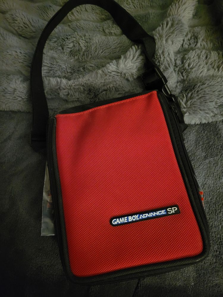 a long, rectangular, red bag with a black strap on the tap. on the red of the bag it says "GAME BOY ADVANCE SP".