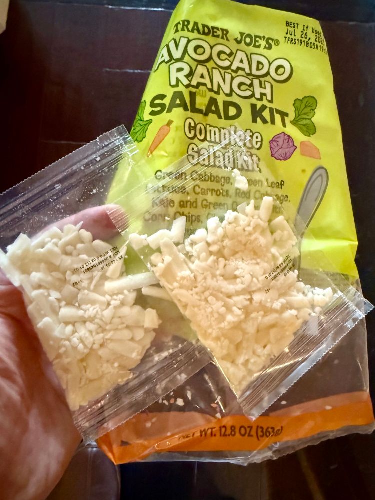Photo of a bag of Trader Joe’s Avocado Ranch Salad Kit showing that it mistakenly contained not one but two packages of shredded cheese.