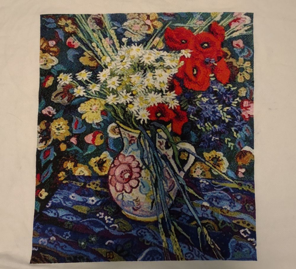 Cross stitch project based on a Van Gogh painting. There is a vase with poppies and daisies on a blue table and flowers on the walls.
