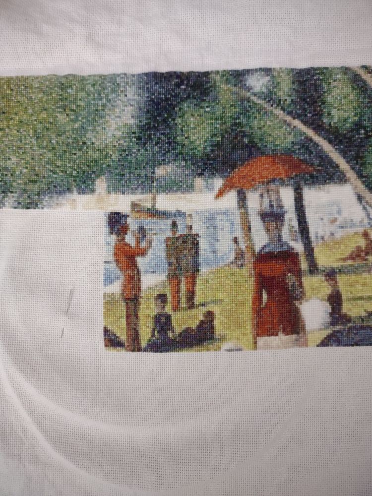 Cross stitch project showing a lake with people enjoying the day.