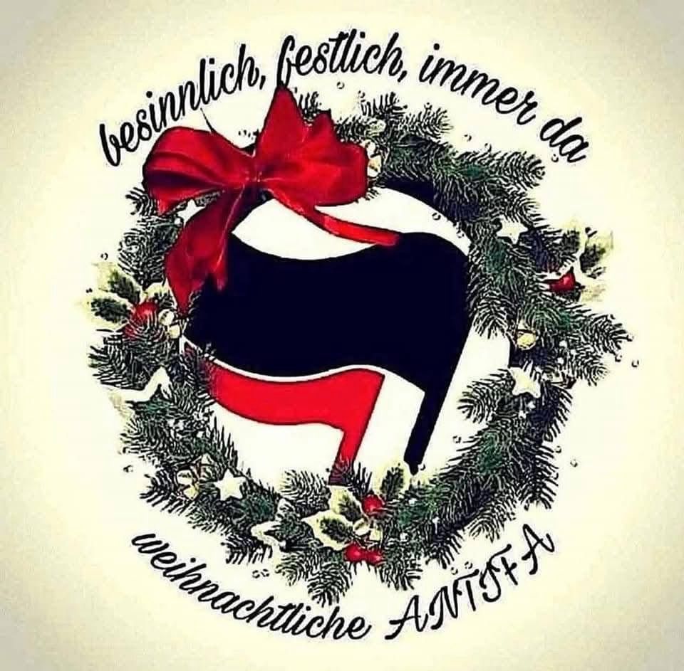 Das Bild zeigt das ANTIFA- Logo,  schwarze Flagge vor  roter Flagge umrnkt von Tannenzweigen und weihnachtssternchen mit dem Spruch:

Besinnlich, festlich, immer nah
Weihnachtliche Antifa