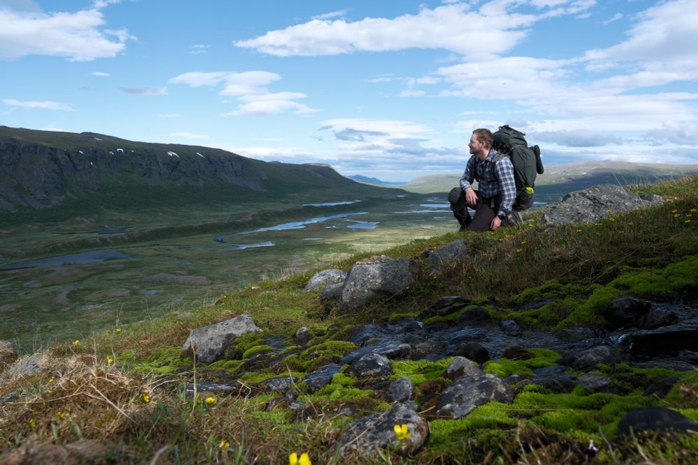View to a valley, river, mountains, blue sky, hiker with a rucksack.