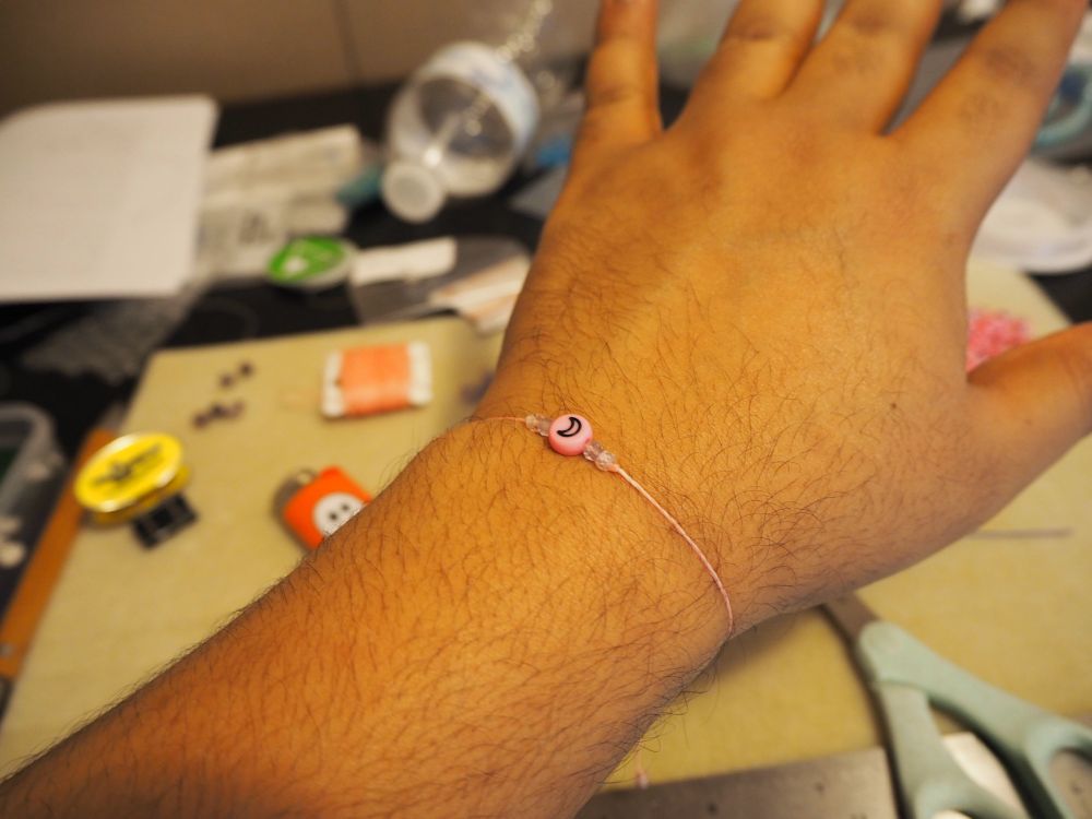A bracelet on my wrist in my atelier, with various jewelry making supplies in the background