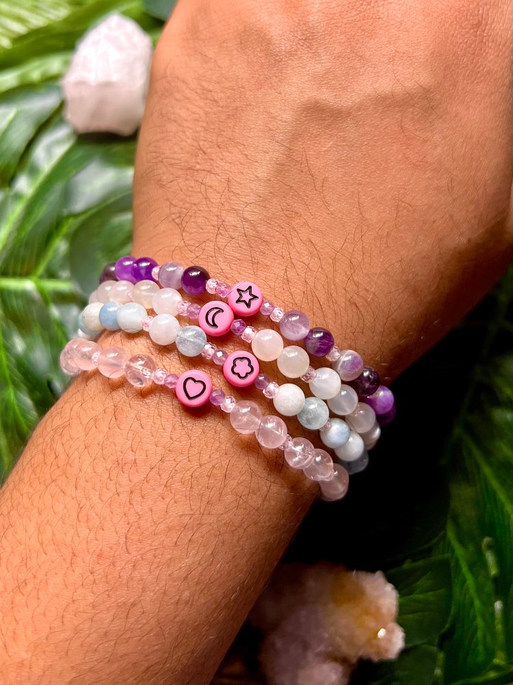 4 multicolored bracelets on my wrist in front of a floral backdrop.