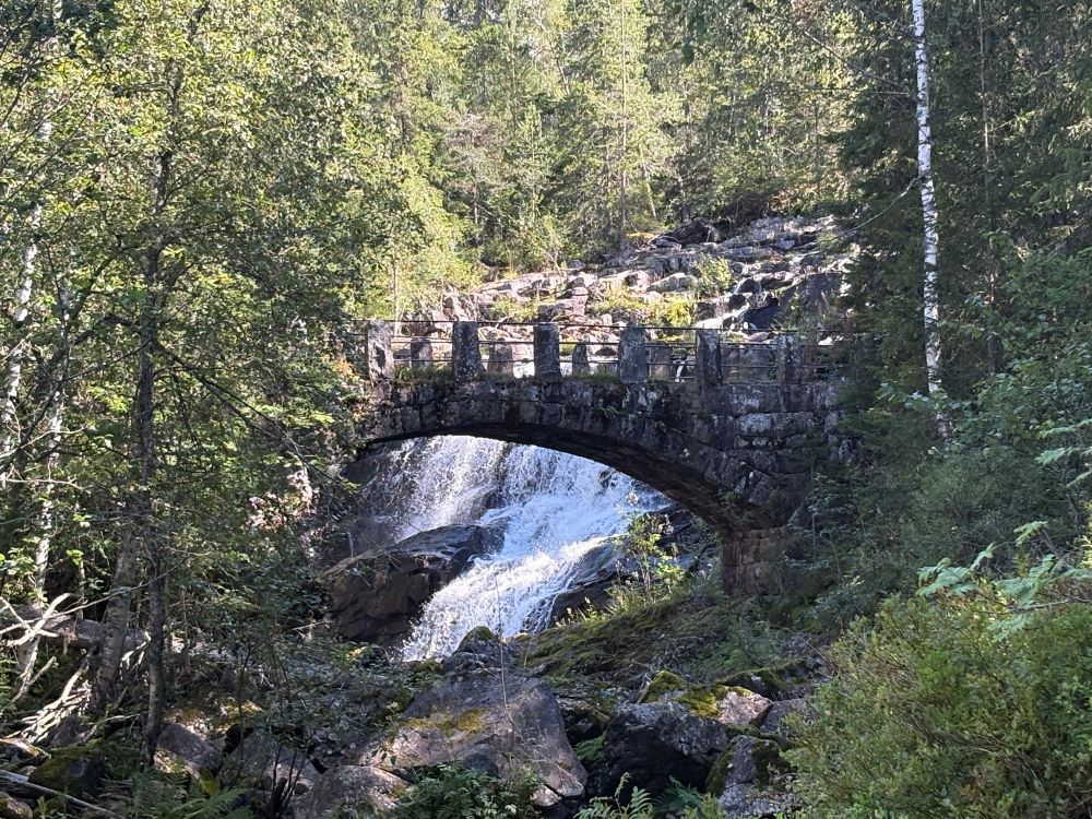 Bilde av Collets Bru på Lillehammer. Det er en steinbro aver en liten foss. Rundt omkring er det skog. Bildet er et yndet fotomotiv g det er lett å forestille seg troll under brua eller diktere som står der og grunner over livets underfundighet.