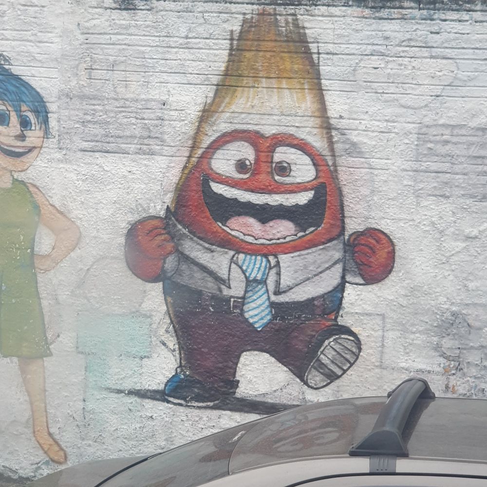 Raiva de divertidamente pintado numa parede

Ele é um blob humanoide vermelho que usa terno, da cabeça sai fogo.

Ele está com uma expressão de feliz