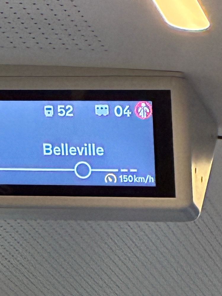 A photo of a destination sign on a train reading "Belleville." In the bottom left is an indicator of the train's speed, which says 150 km/h.