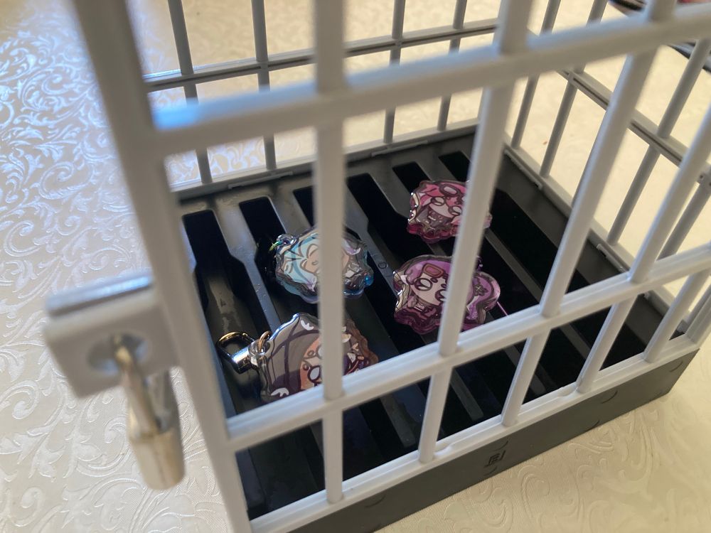 a photo of four chibis of the worms placed inside a small locked cage